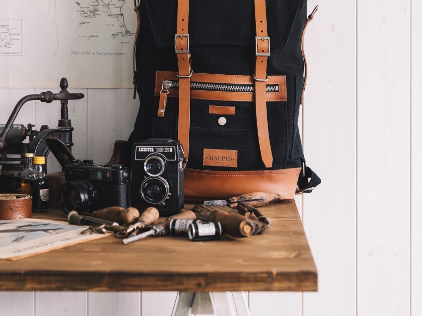backpack, cameras, tools, maps, hat